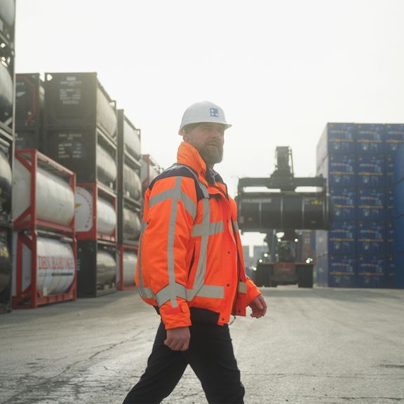 Ron Kuijpers lopend over het terrein van Broekman Logistics, met chemiecontainers op de achtergrond